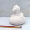 Ceramic baby dragone to paint sitting on a blue table with a lacy ecru curtain behind it.  There are two used paint brushes in front of it.